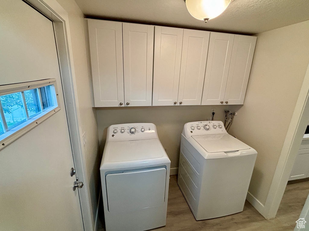Washroom featuring cabinet space, washer and clothes dryer, and light wood-style floors