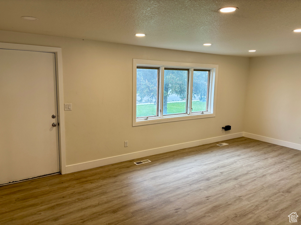 Empty room featuring wood finished floors, baseboards, recessed lighting, and a textured ceiling