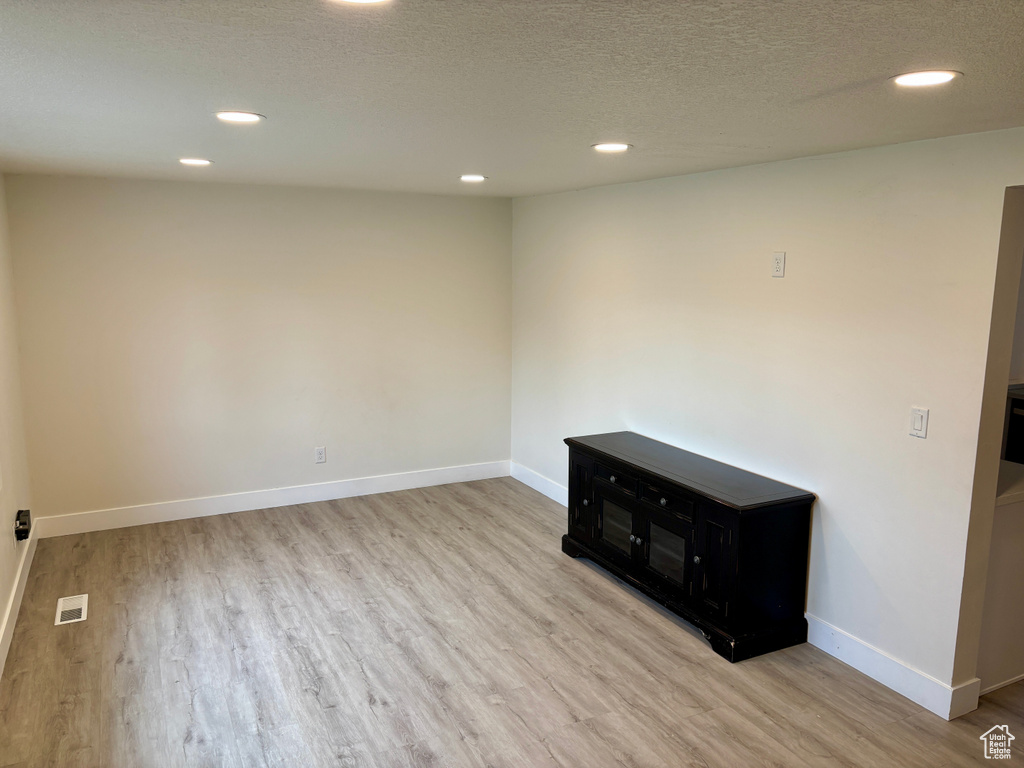 Unfurnished room with wood finished floors, recessed lighting, baseboards, and a textured ceiling