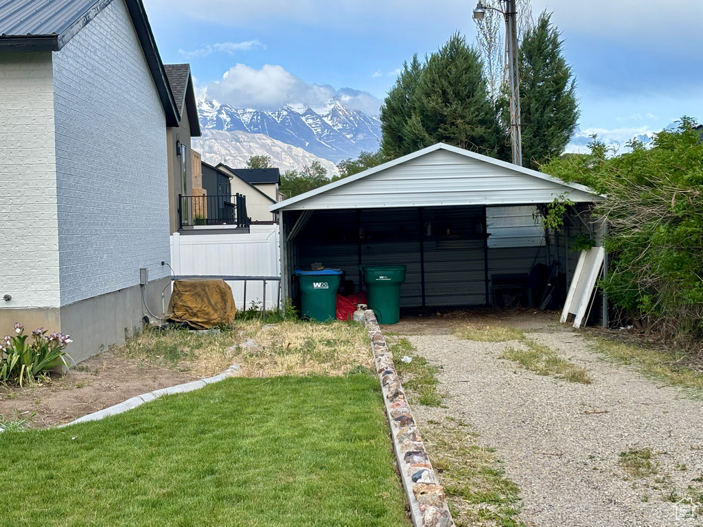 View of outdoor structure with dirt driveway, a mountain view, and a carport