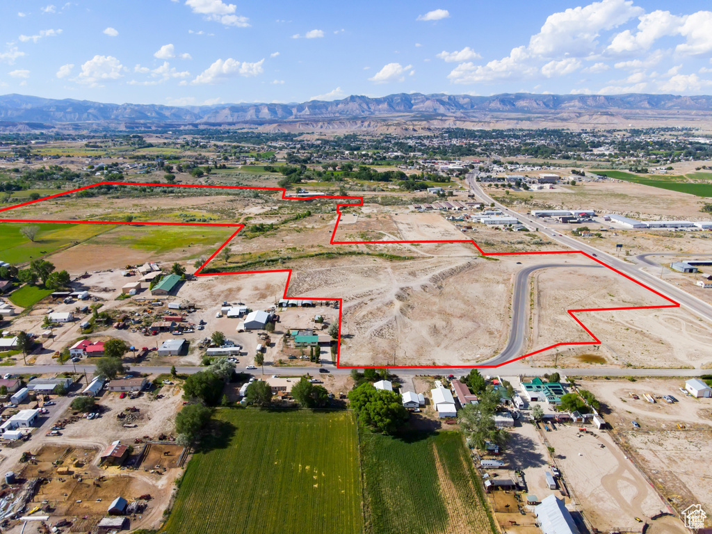 Aerial view of property and surrounding area with property parcel outlined and a mountainous background