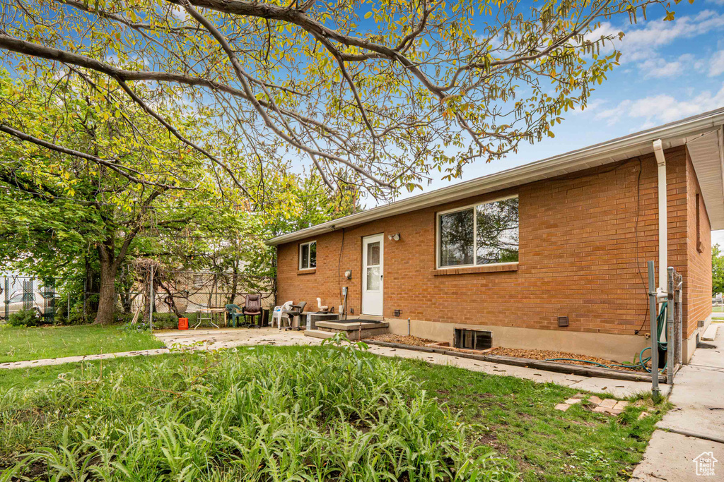 View of front facade featuring brick siding, a patio area, fence, and a front yard