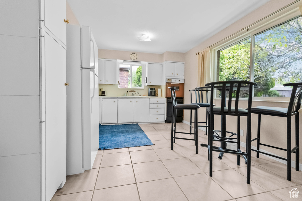 Kitchen with white cabinets, oven, a sink, light countertops, and freestanding refrigerator