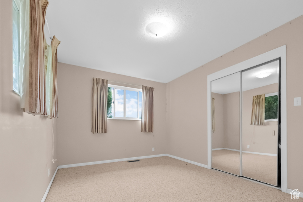 Unfurnished bedroom featuring carpet floors, baseboards, visible vents, and a closet