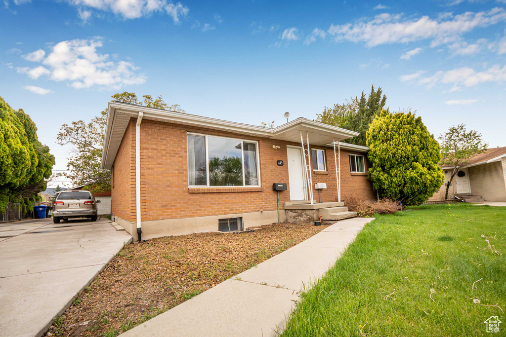View of front of home with brick siding, driveway, and a front yard