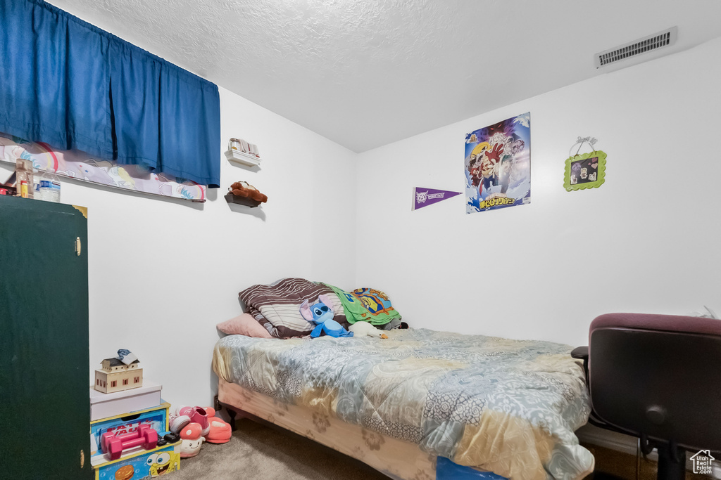 Bedroom featuring a textured ceiling, visible vents, and carpet