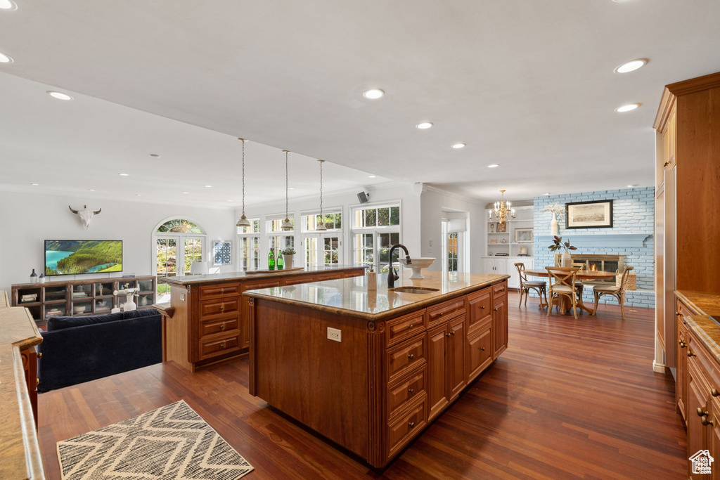 Kitchen featuring a sink, a large island with sink, brown cabinets, recessed lighting, and dark wood finished floors