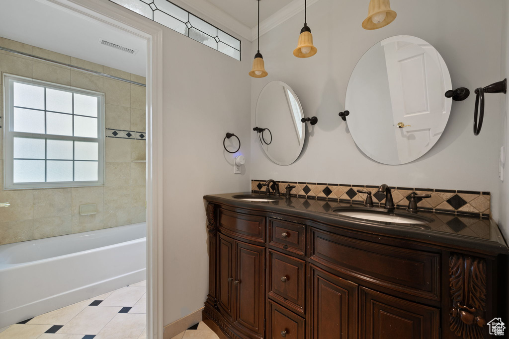 Bathroom with tile patterned floors, double vanity, ornamental molding, and bathtub / shower combination