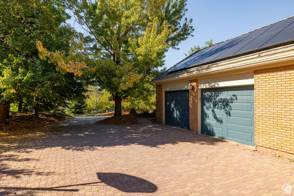 Garage with solar panels and decorative driveway