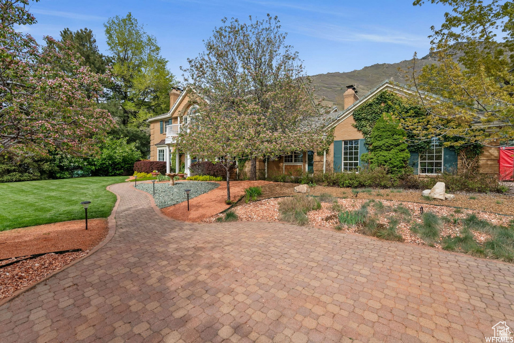 View of front of property featuring a chimney, a mountain view, and a front yard