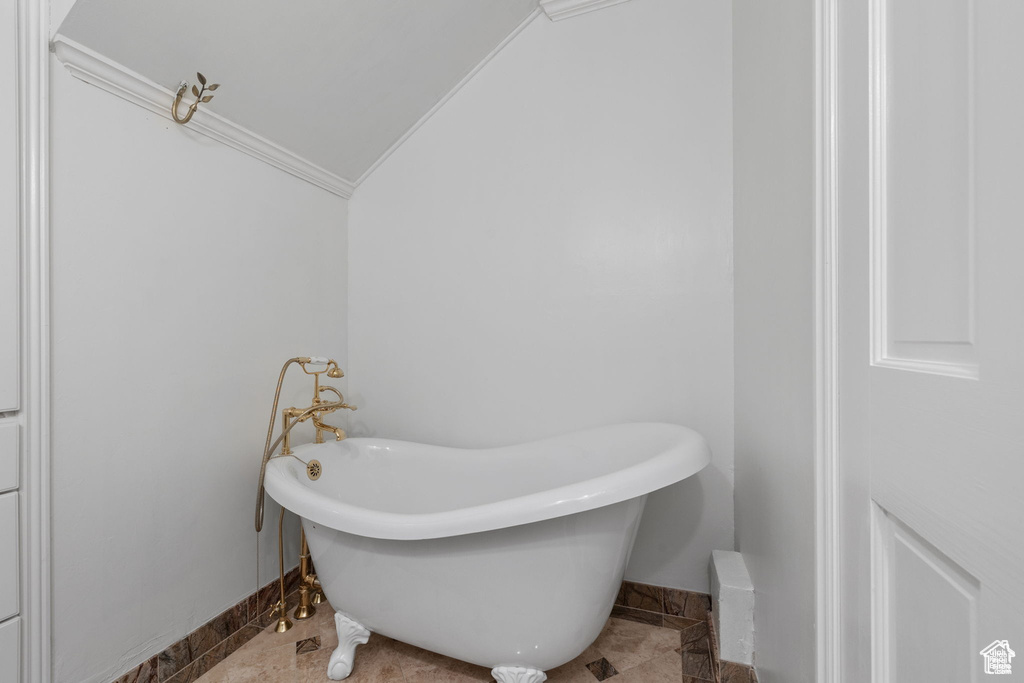 Full bathroom with a soaking tub, vaulted ceiling, and baseboards