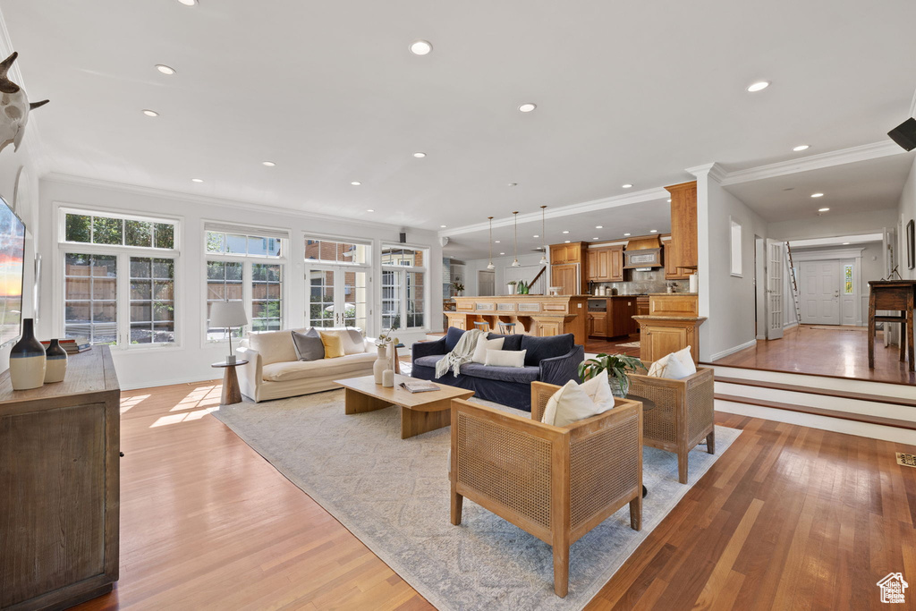 Living area featuring ornamental molding, light wood-style floors, recessed lighting, and baseboards