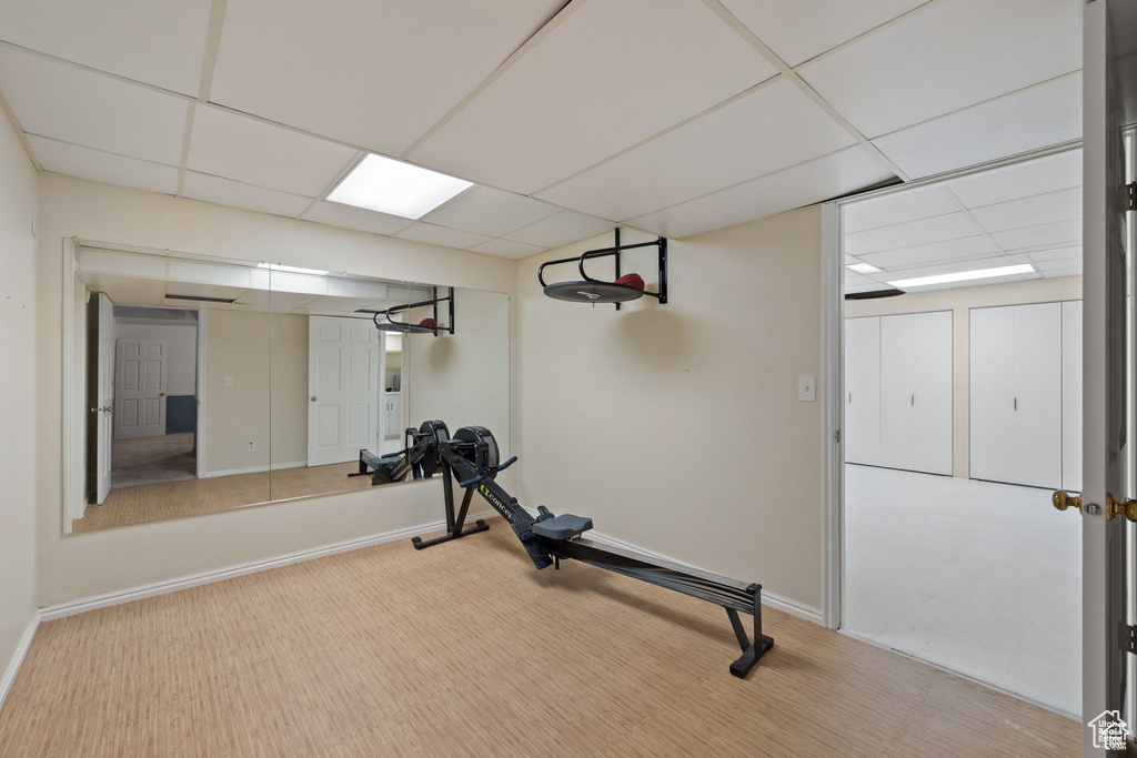 Workout area featuring a drop ceiling, baseboards, and carpet floors