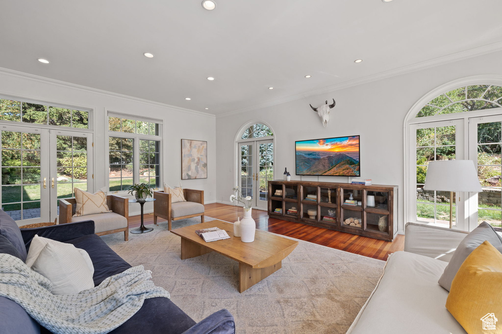 Living area with french doors, ornamental molding, wood finished floors, and recessed lighting