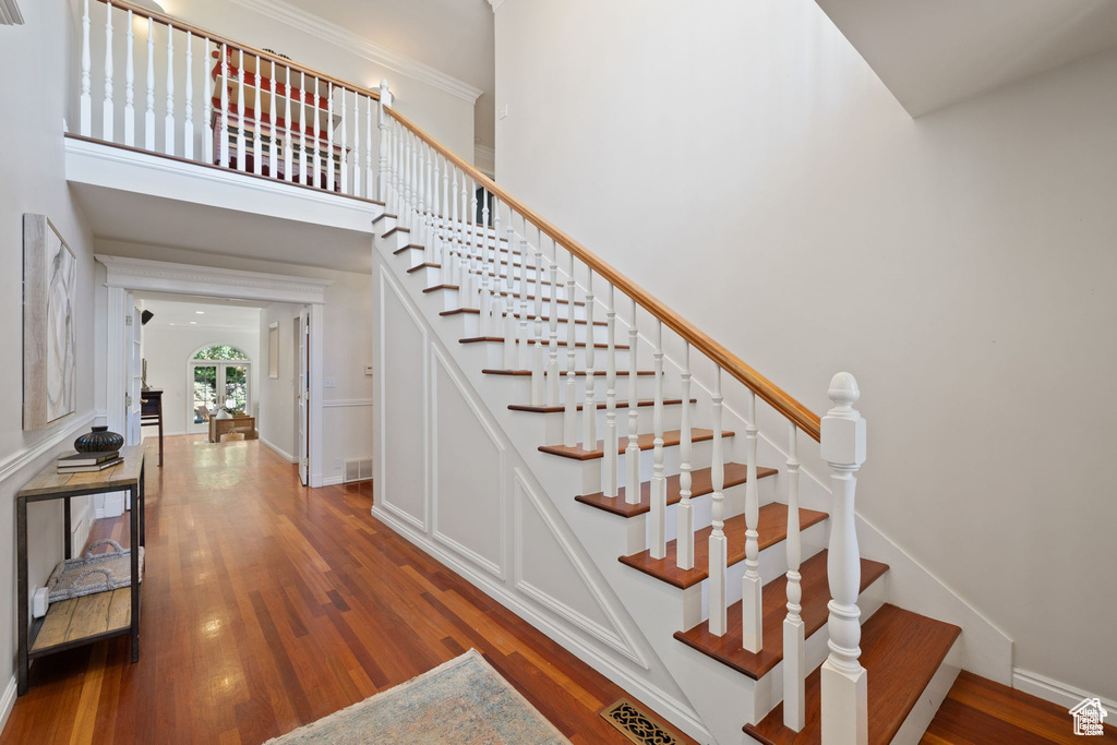 Staircase featuring wood finished floors, baseboards, and a high ceiling