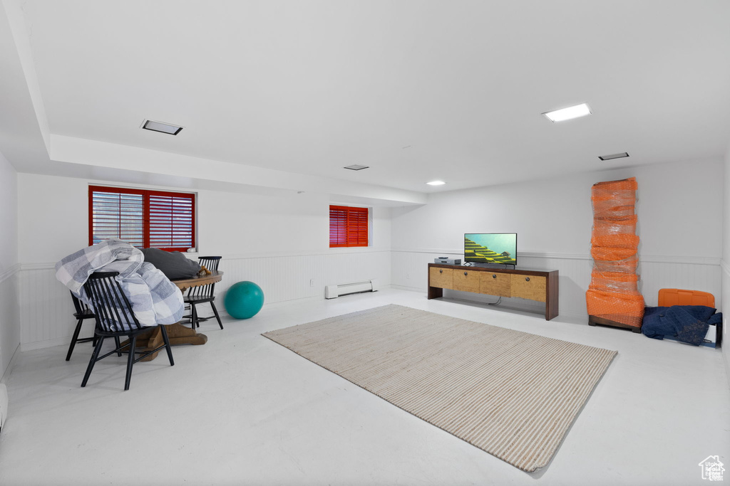 Workout area with baseboard heating and a wainscoted wall