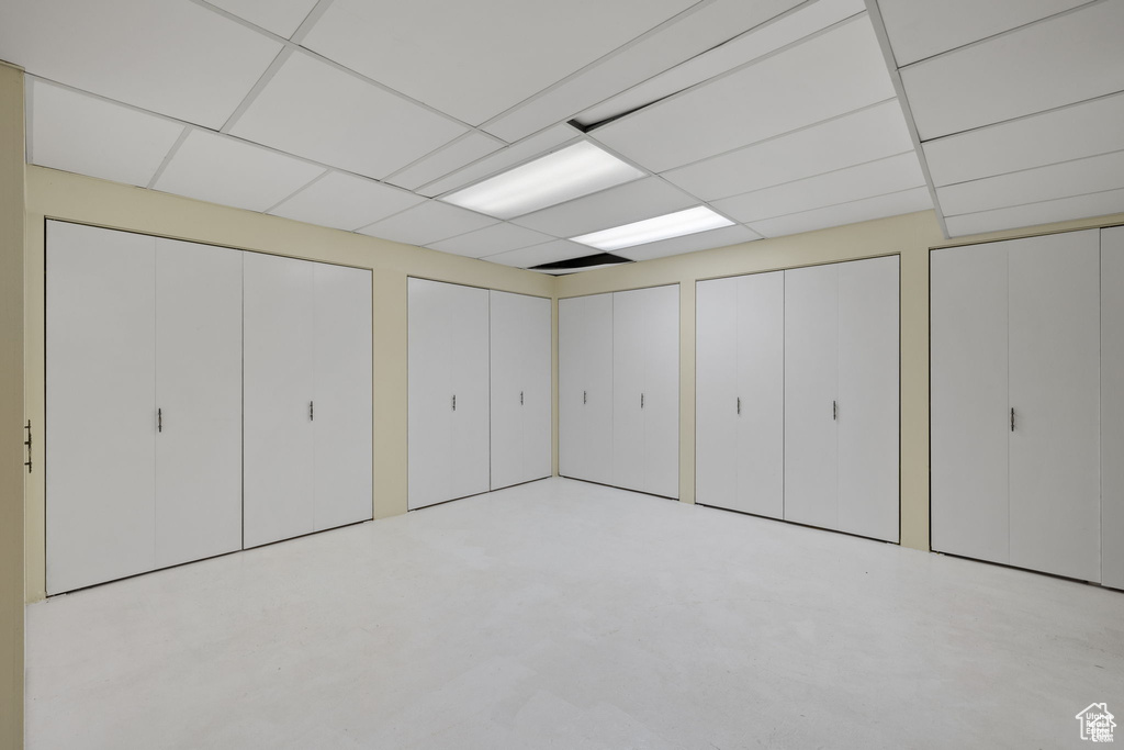 Unfurnished bedroom featuring two closets, a drop ceiling, and concrete flooring