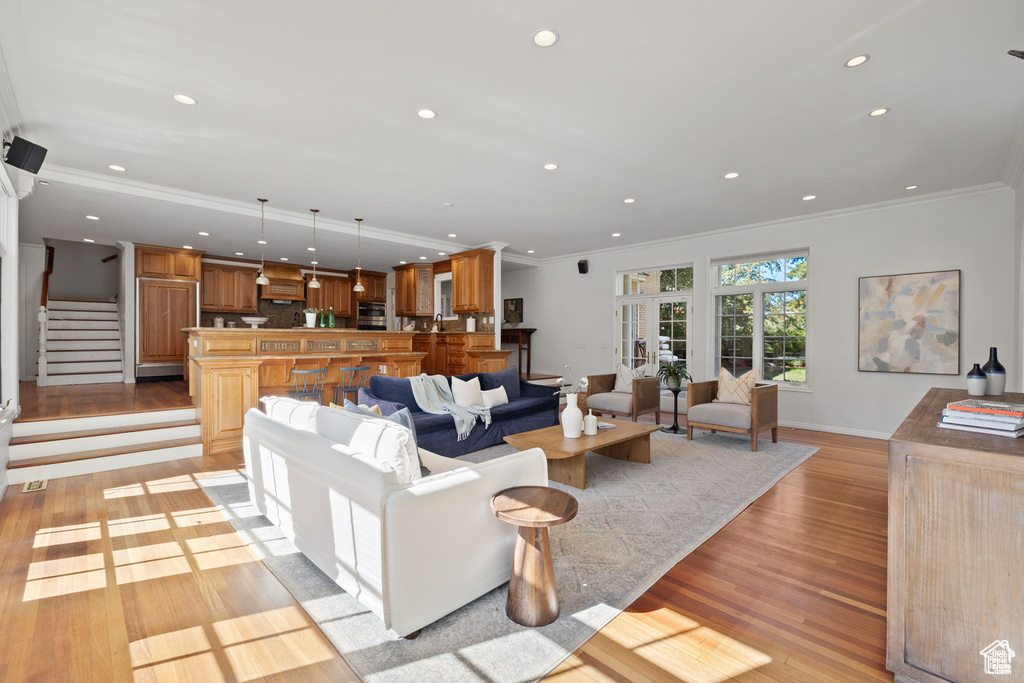 Living area featuring crown molding, light wood-style floors, recessed lighting, stairway, and baseboards