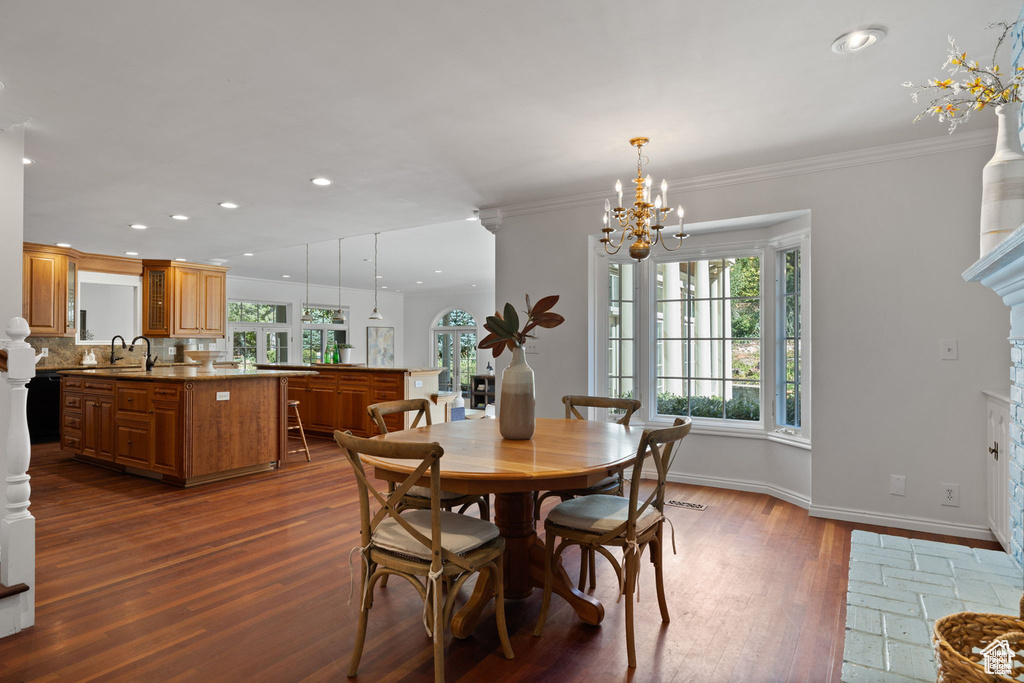Dining space with dark wood-type flooring, a chandelier, recessed lighting, baseboards, and crown molding