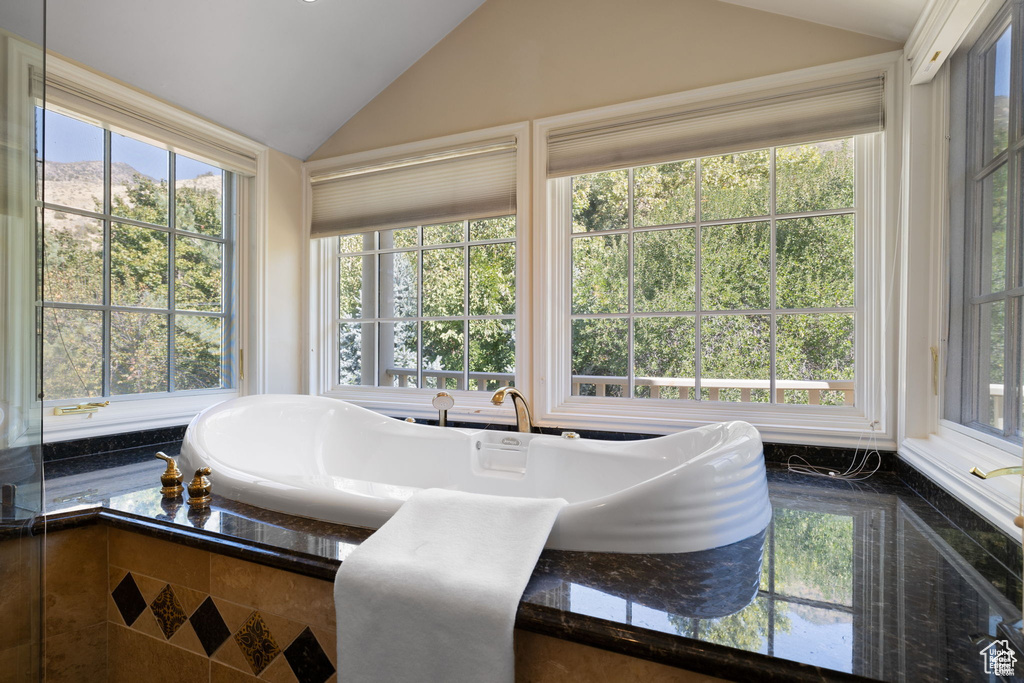 Bathroom with lofted ceiling and a tub
