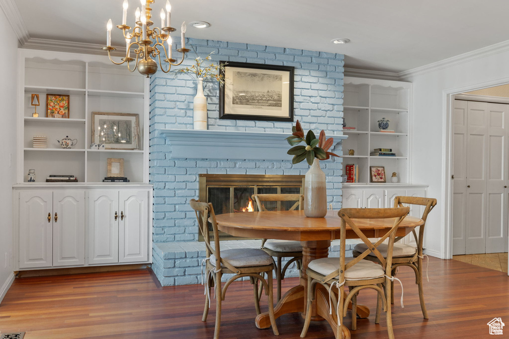 Dining room with ornamental molding, wood finished floors, a chandelier, built in features, and baseboards