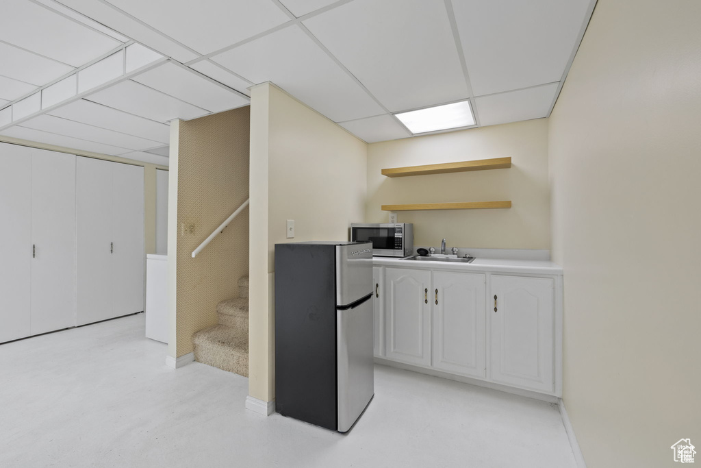 Kitchen featuring appliances with stainless steel finishes, open shelves, a sink, white cabinets, and light countertops