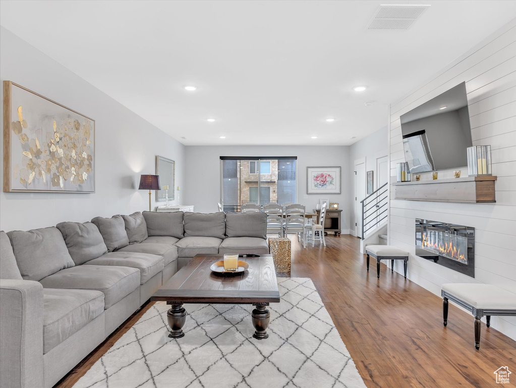 Living room with wood finished floors, recessed lighting, and a glass covered fireplace