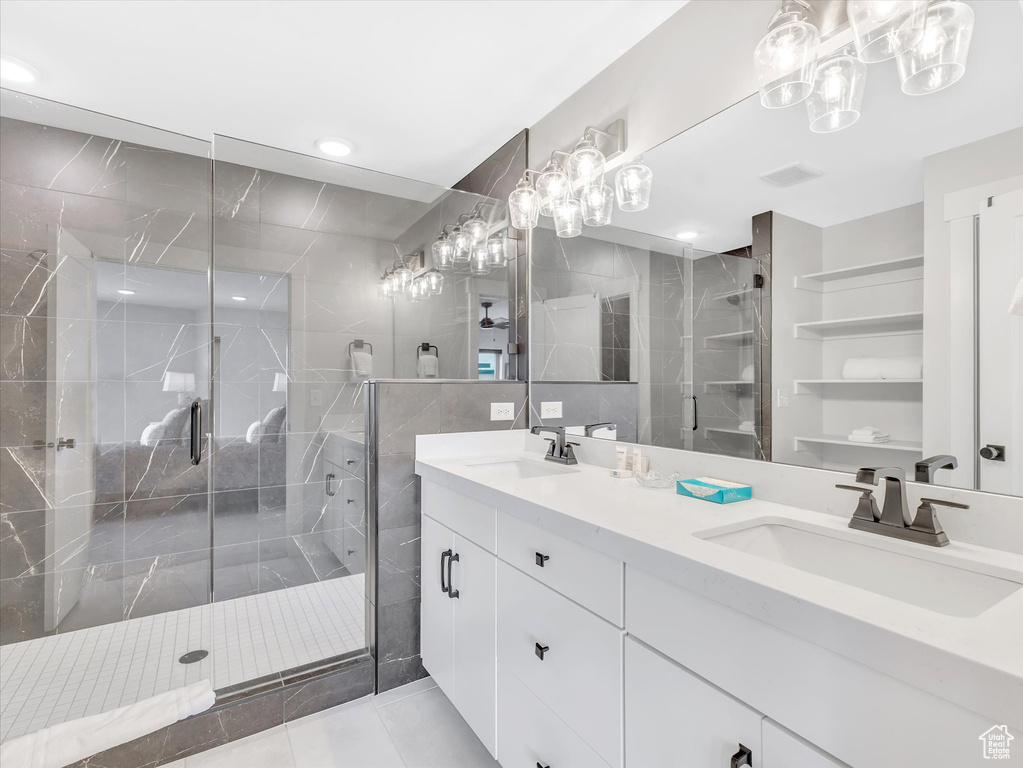 Full bathroom with a shower stall, double vanity, tile patterned flooring, and tile walls