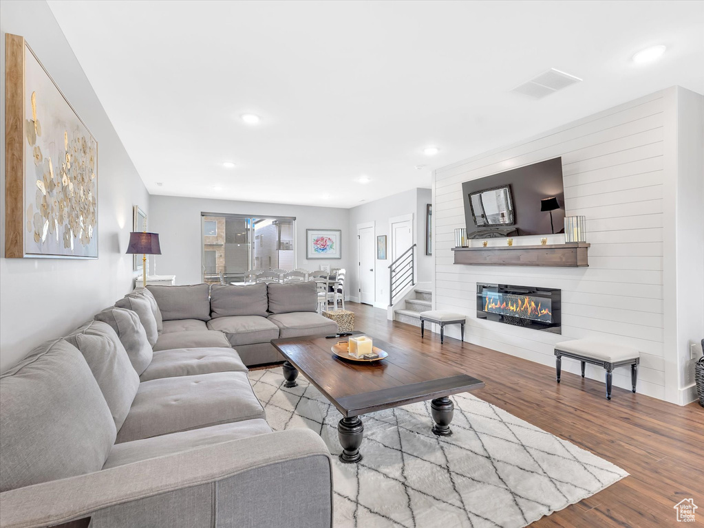 Living area featuring wood finished floors, recessed lighting, a fireplace, and stairs