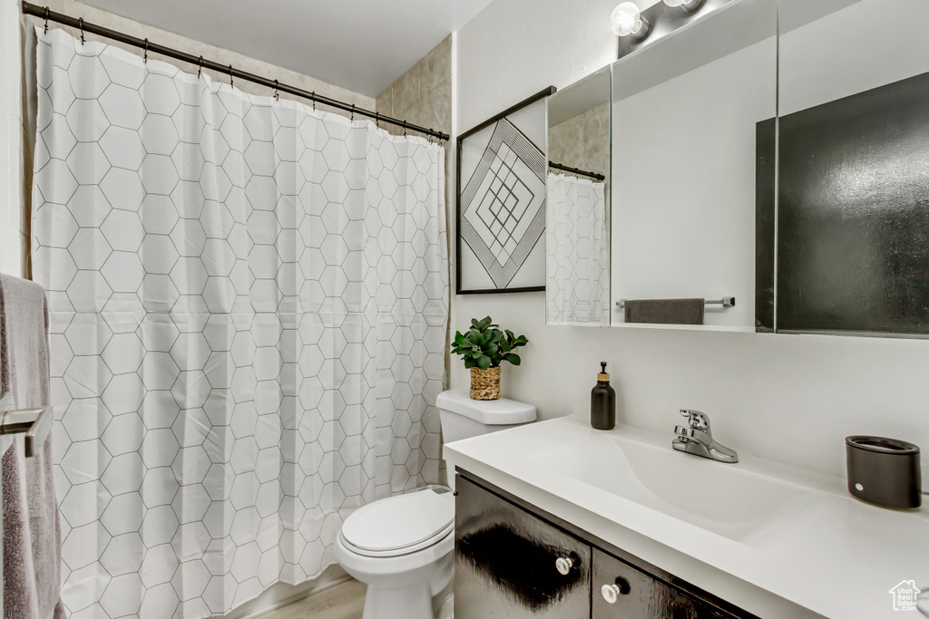 Full bath featuring toilet, vanity, and curtained shower