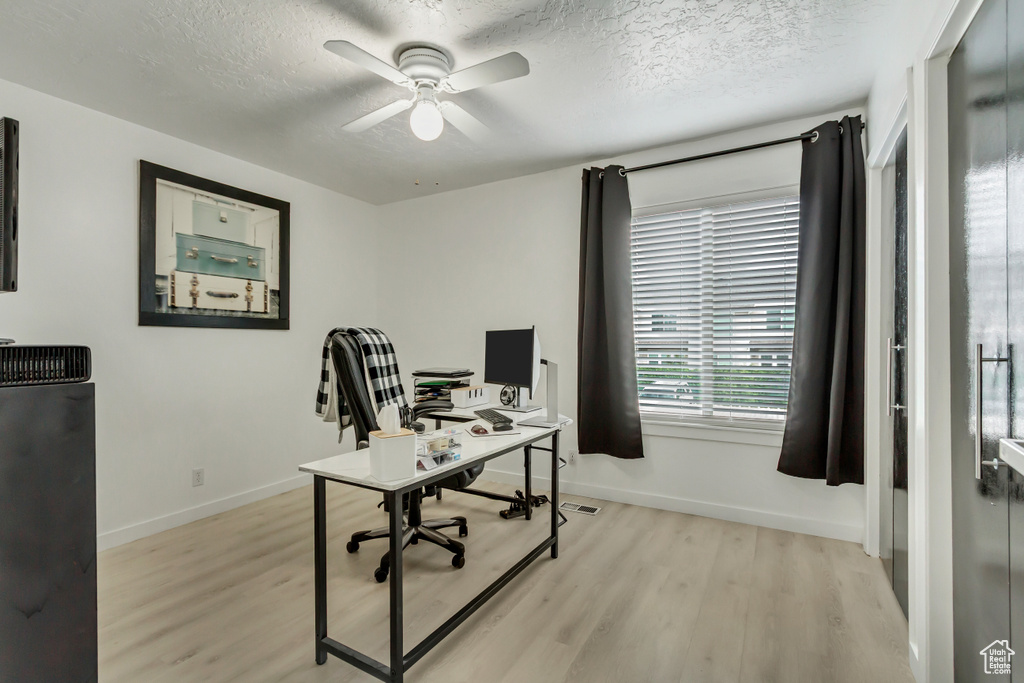 Office space with light wood-type flooring, baseboards, a ceiling fan, and a textured ceiling