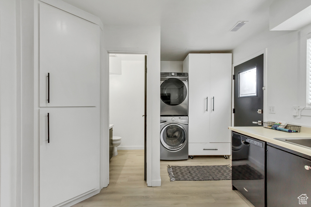 Laundry room featuring estacked washer and dryer and light wood-type flooring