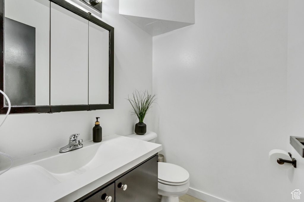 Bathroom featuring toilet, vanity, and baseboards