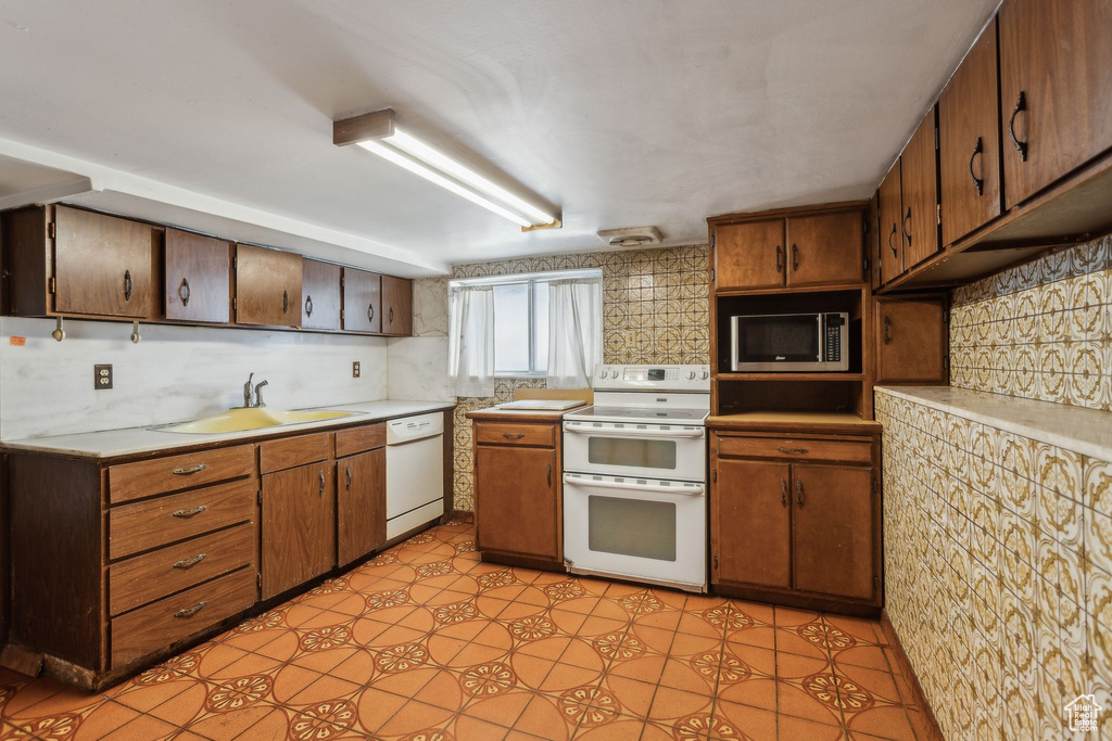 Kitchen with white appliances, a sink, light countertops, and decorative backsplash