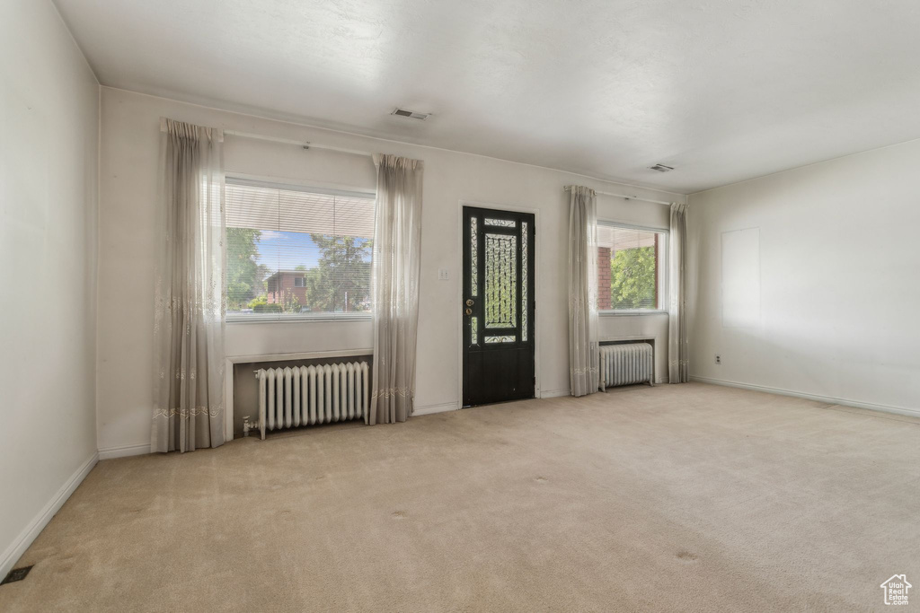 Carpeted empty room with radiator and baseboards