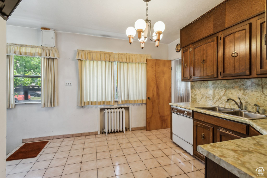 Kitchen with radiator heating unit, a sink, light countertops, a chandelier, and backsplash