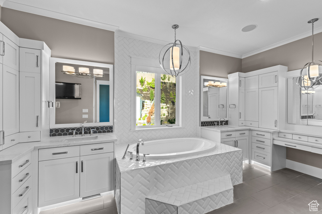 Full bath featuring a chandelier, crown molding, a bath, tile patterned floors, and two vanities