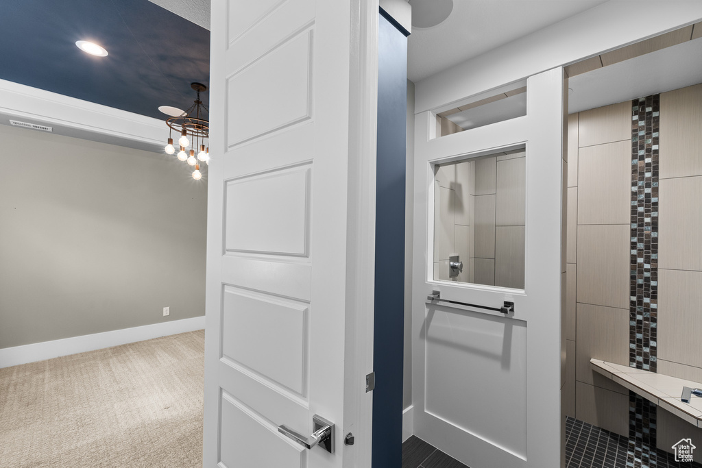 Bathroom with a chandelier, a tile shower, and baseboards