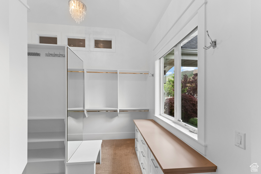Spacious closet featuring vaulted ceiling, light carpet, and a chandelier
