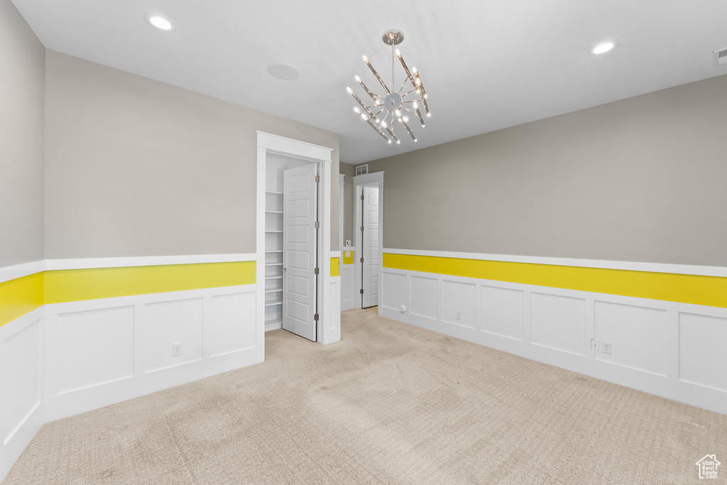 Carpeted spare room with a decorative wall, wainscoting, recessed lighting, and a chandelier