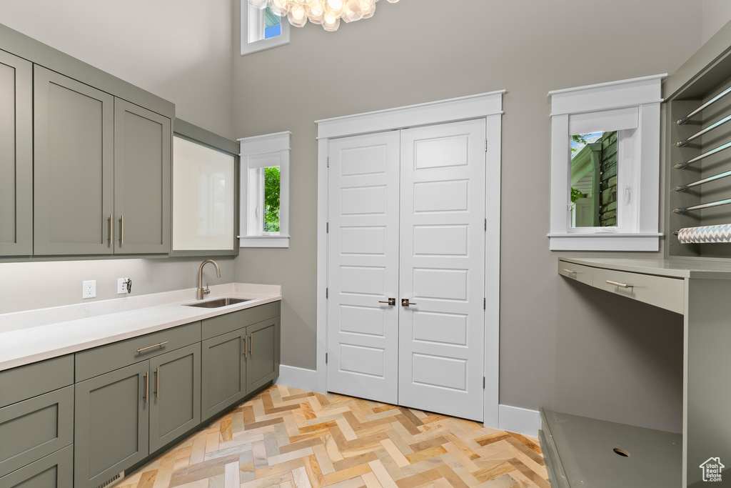 Clothes washing area featuring a sink, healthy amount of natural light, a towering ceiling, baseboards, and a chandelier