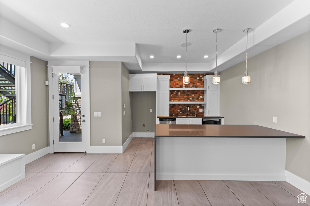 Kitchen featuring dark countertops, decorative light fixtures, white cabinets, a peninsula, and recessed lighting