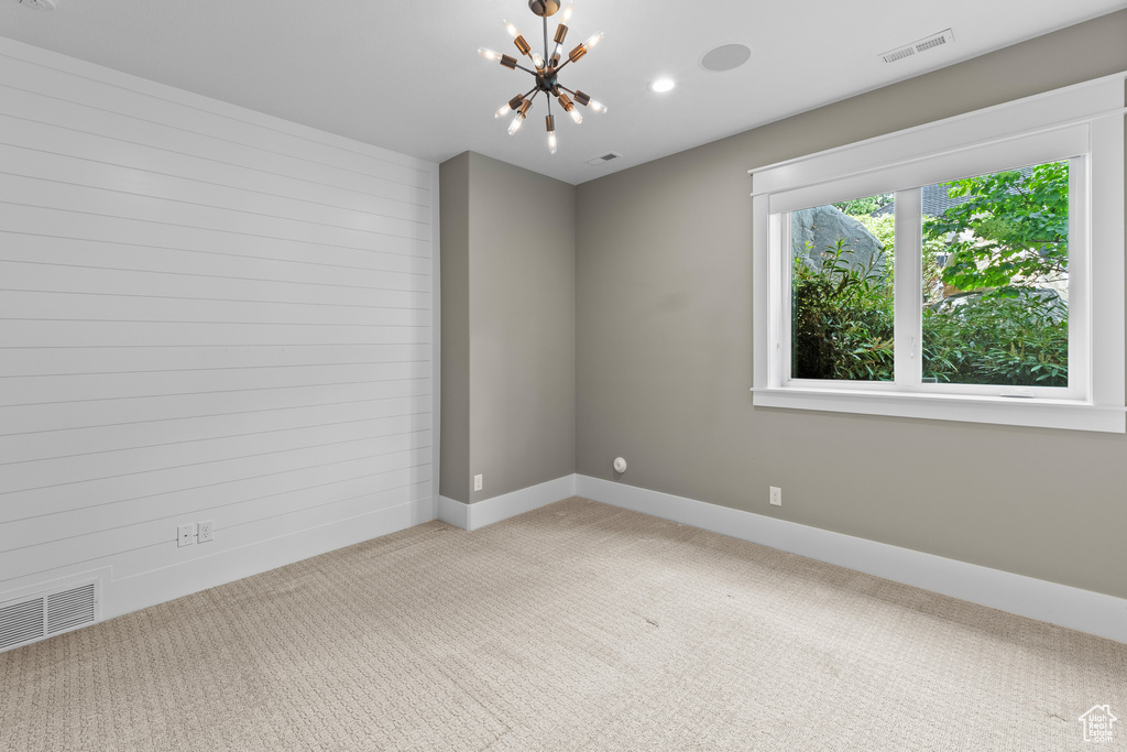 Unfurnished room featuring a chandelier, light colored carpet, baseboards, and recessed lighting
