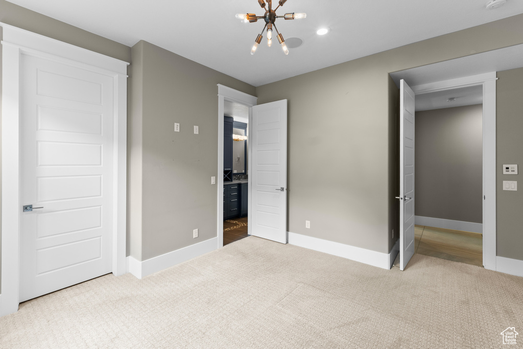 Unfurnished bedroom featuring carpet floors, a chandelier, and baseboards