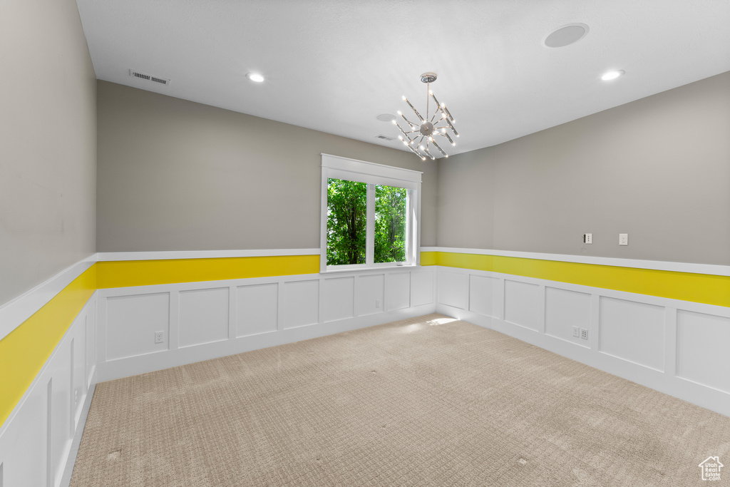 Unfurnished room featuring carpet floors, wainscoting, a chandelier, recessed lighting, and a decorative wall