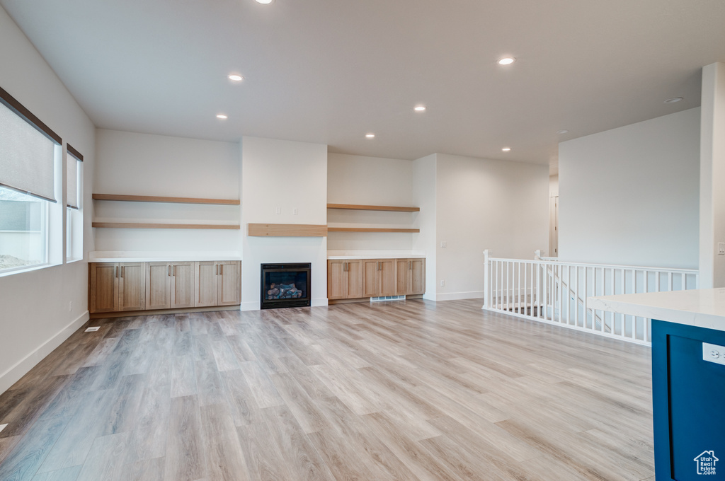 Unfurnished living room with light wood-style flooring, recessed lighting, baseboards, and a fireplace