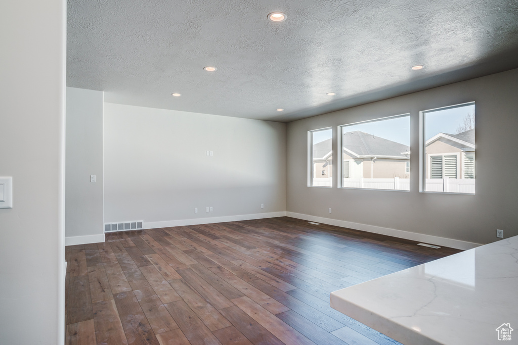 Unfurnished room featuring a textured ceiling, wood-type flooring, recessed lighting, and baseboards