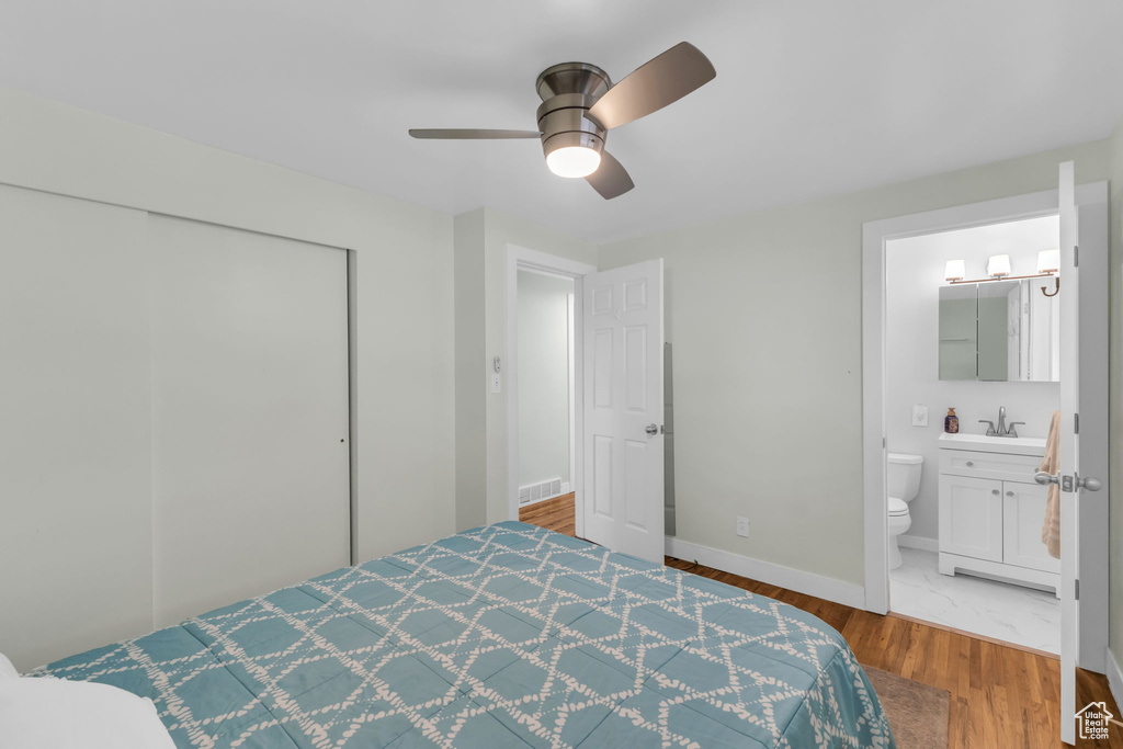 Bedroom with a sink, wood finished floors, a closet, baseboards, and ensuite bath
