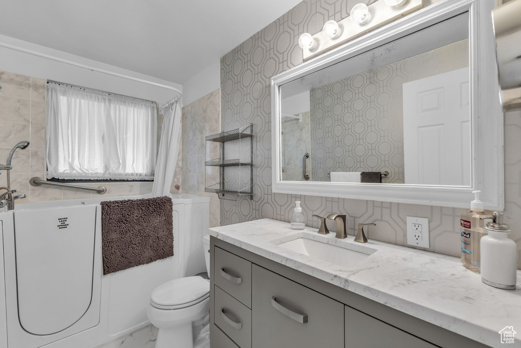 Full bath featuring vanity, toilet, marble finish floors, and a bath