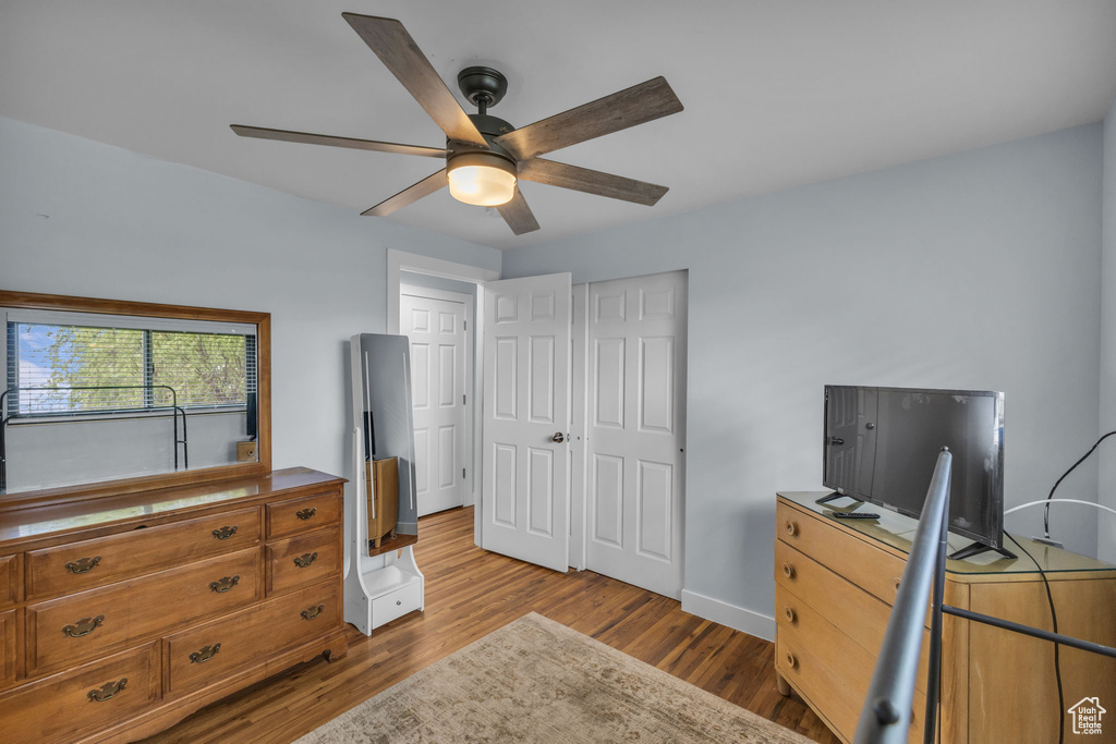 Bedroom featuring wood finished floors, baseboards, a ceiling fan, and a closet